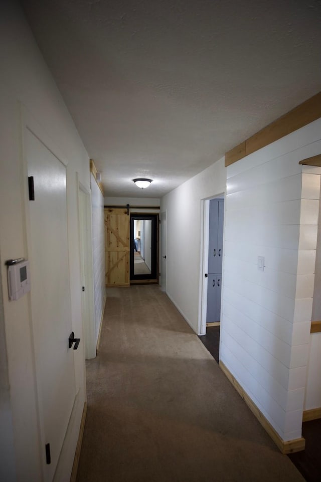 hallway featuring light colored carpet and a barn door