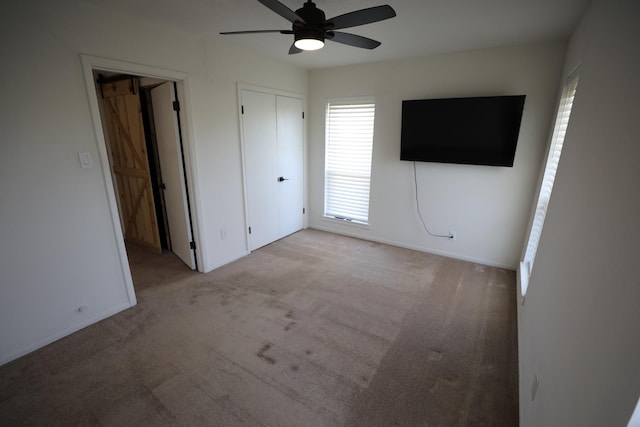 unfurnished bedroom with a ceiling fan, light carpet, and baseboards