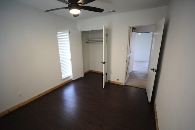 unfurnished bedroom featuring baseboards, visible vents, ceiling fan, dark wood-style flooring, and a closet