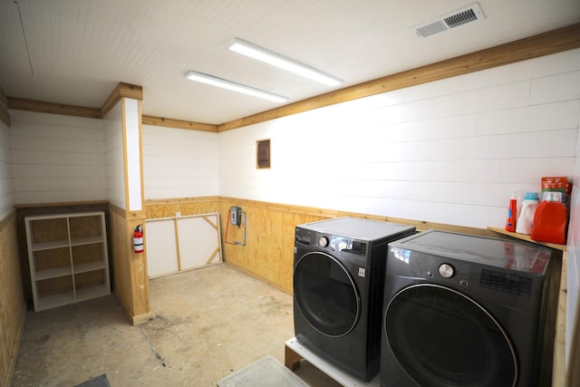 clothes washing area featuring laundry area, wooden walls, visible vents, and washing machine and clothes dryer