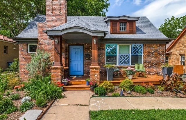 bungalow-style home featuring a shingled roof, brick siding, and a chimney