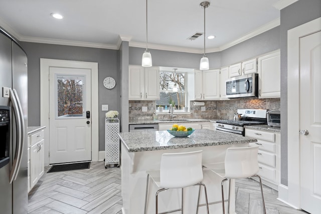 kitchen featuring appliances with stainless steel finishes, visible vents, crown molding, and decorative backsplash