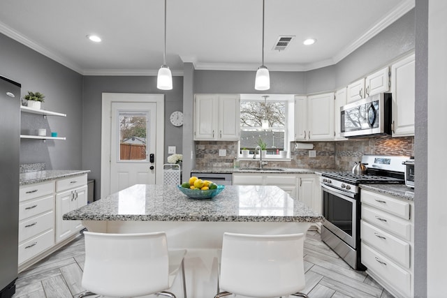 kitchen featuring appliances with stainless steel finishes, a sink, visible vents, and crown molding