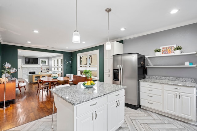 kitchen with white cabinets, crown molding, and stainless steel refrigerator with ice dispenser