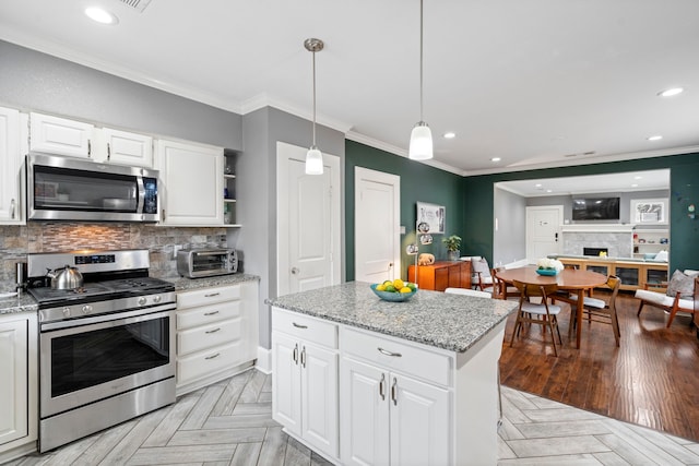 kitchen with pendant lighting, crown molding, stainless steel appliances, decorative backsplash, and light stone countertops