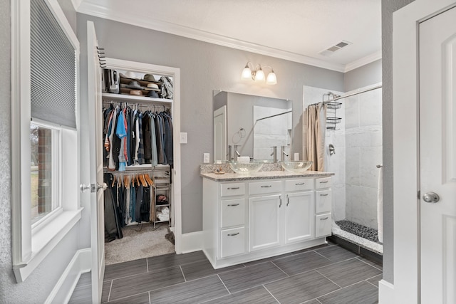 bathroom featuring ornamental molding, a tile shower, vanity, and a walk in closet