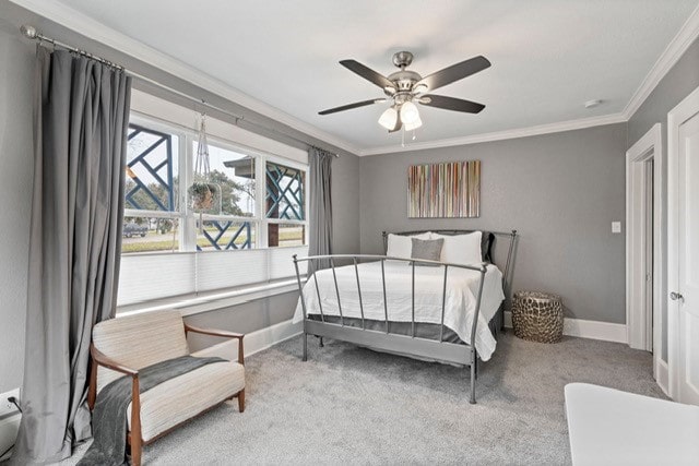 carpeted bedroom featuring baseboards, ornamental molding, and ceiling fan