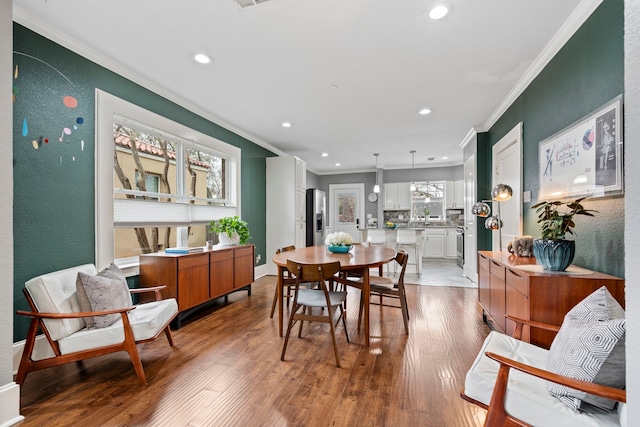 dining room featuring light wood-type flooring and crown molding