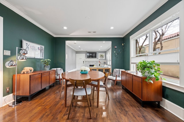 dining space with crown molding, dark wood-style flooring, a fireplace, and baseboards