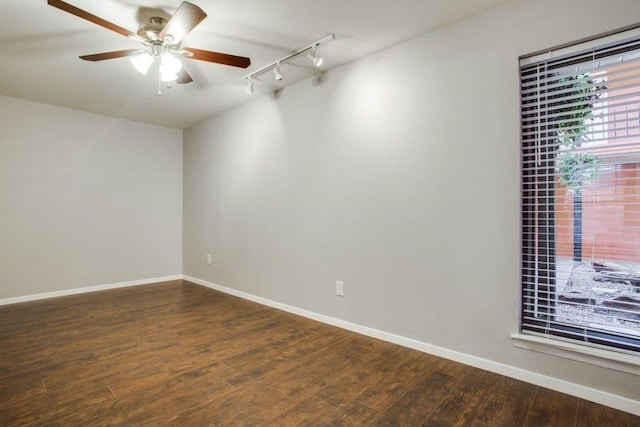 empty room featuring a ceiling fan, rail lighting, baseboards, and wood finished floors