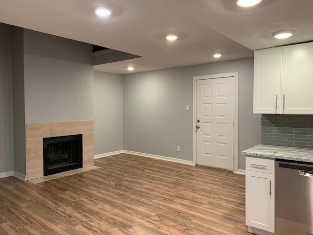 interior space featuring a tile fireplace, recessed lighting, wood finished floors, and baseboards