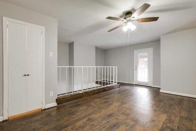 empty room featuring wood finished floors, a ceiling fan, and baseboards