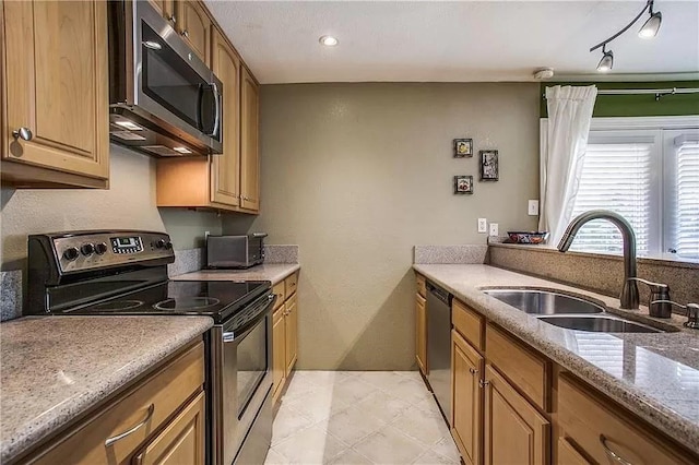 kitchen featuring stainless steel appliances, a sink, and light stone countertops