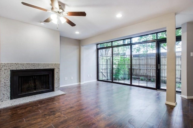 unfurnished living room featuring a premium fireplace, baseboards, wood finished floors, and recessed lighting