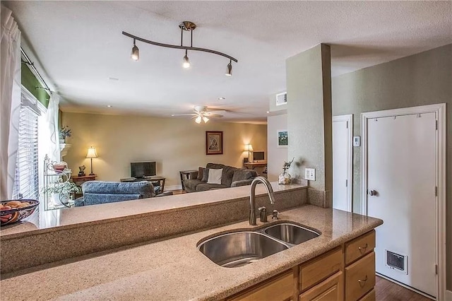 kitchen featuring open floor plan, visible vents, a sink, and light stone countertops