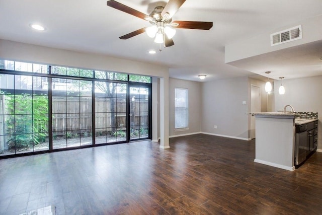 unfurnished living room with dark wood-style floors, baseboards, visible vents, and a healthy amount of sunlight