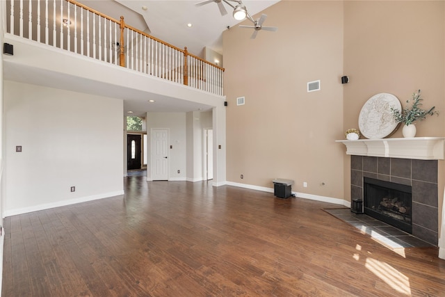 unfurnished living room featuring ceiling fan, a fireplace, wood finished floors, visible vents, and baseboards