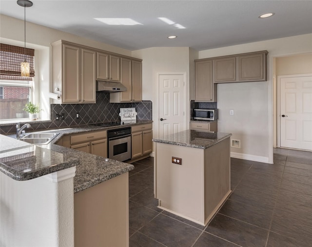 kitchen with under cabinet range hood, stainless steel appliances, dark tile patterned flooring, a sink, and dark stone counters