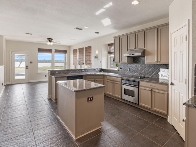 kitchen with black electric cooktop, oven, under cabinet range hood, a peninsula, and visible vents