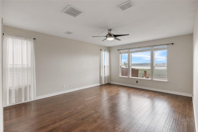 spare room featuring dark wood-style floors, baseboards, visible vents, and a ceiling fan