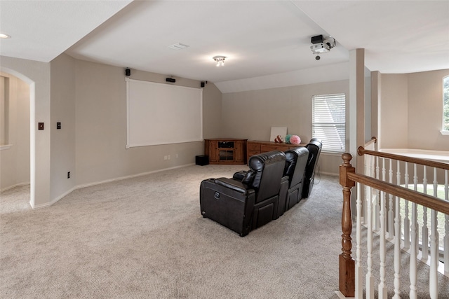 carpeted home theater room with arched walkways, vaulted ceiling, and baseboards