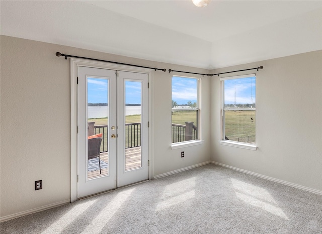 carpeted spare room featuring french doors and baseboards