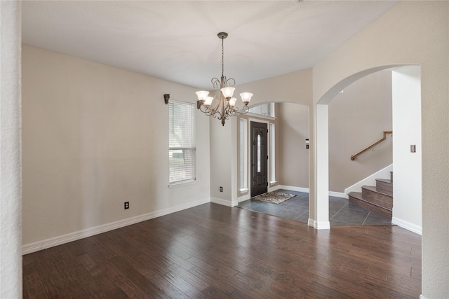 foyer entrance with an inviting chandelier, stairway, baseboards, and wood finished floors