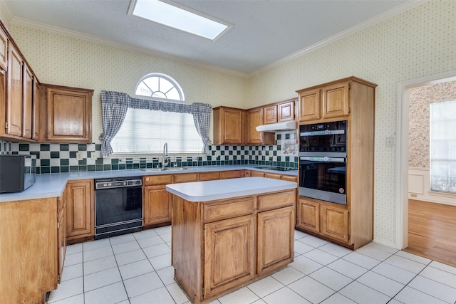 kitchen featuring a wainscoted wall, light tile patterned floors, a sink, black appliances, and wallpapered walls