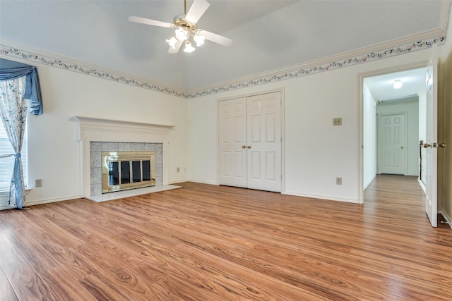 unfurnished living room with lofted ceiling, a ceiling fan, baseboards, light wood-style floors, and a tiled fireplace