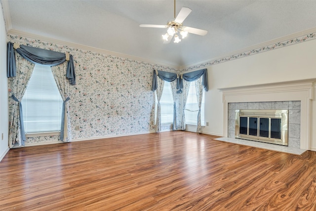 unfurnished living room with wallpapered walls, ornamental molding, wood finished floors, and a tile fireplace