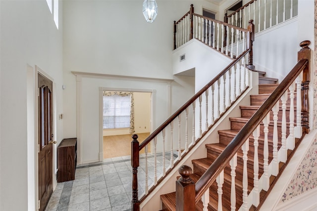 foyer entrance featuring baseboards, visible vents, and a high ceiling