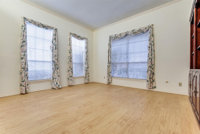 empty room with ornamental molding, a textured ceiling, baseboards, and wood finished floors