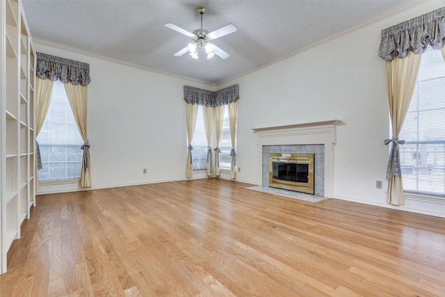 unfurnished living room featuring baseboards, a tiled fireplace, ceiling fan, ornamental molding, and light wood-style floors