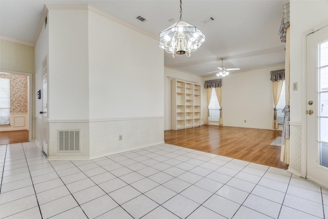 empty room with built in features, a wainscoted wall, visible vents, light tile patterned flooring, and wallpapered walls