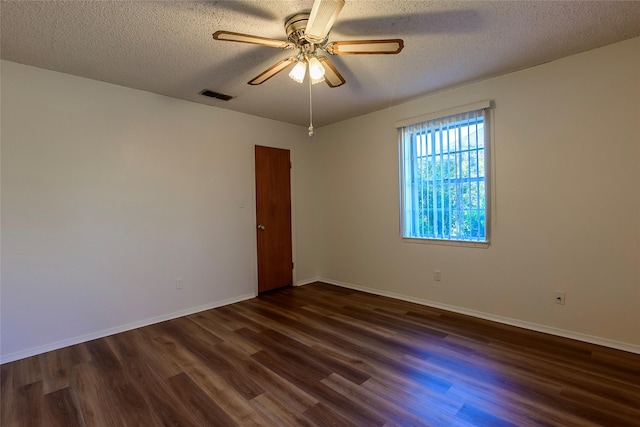 spare room featuring a textured ceiling, dark wood-style flooring, visible vents, baseboards, and a ceiling fan