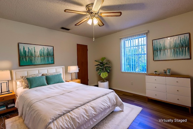 bedroom featuring baseboards, visible vents, a ceiling fan, wood finished floors, and a textured ceiling