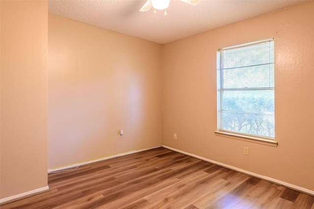 spare room featuring a ceiling fan, a textured ceiling, baseboards, and wood finished floors