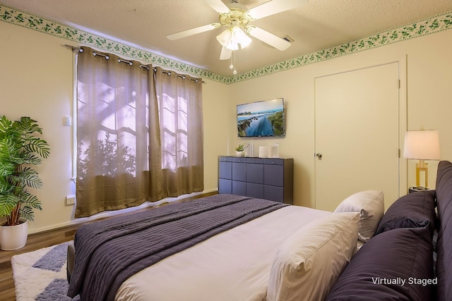 bedroom with a textured ceiling, a ceiling fan, and wood finished floors