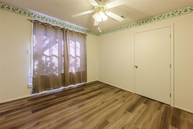 spare room with ceiling fan, a textured ceiling, and wood finished floors