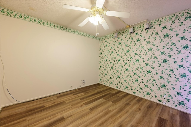 unfurnished room with wallpapered walls, a textured ceiling, a ceiling fan, and wood finished floors