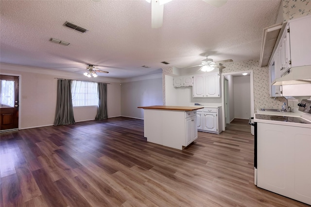 kitchen with a textured ceiling, white cabinets, open floor plan, range, and dark wood finished floors