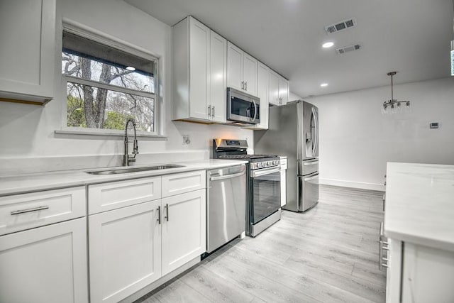 kitchen featuring stainless steel appliances, light countertops, visible vents, and a sink