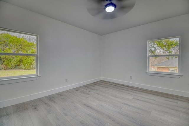 empty room with light wood-style floors, plenty of natural light, and baseboards