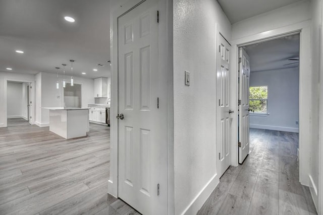 corridor featuring recessed lighting, light wood-style flooring, and baseboards