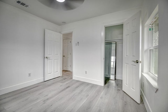 unfurnished bedroom featuring baseboards, a ceiling fan, visible vents, and light wood-style floors