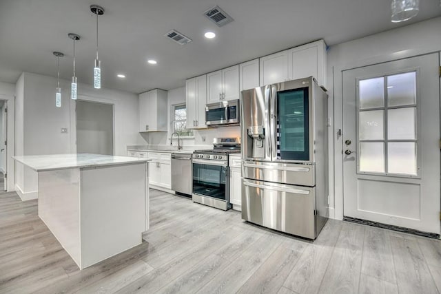 kitchen featuring appliances with stainless steel finishes, visible vents, light wood finished floors, and white cabinetry