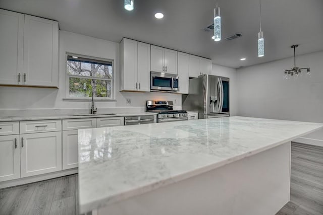 kitchen featuring appliances with stainless steel finishes, light wood-type flooring, a sink, and visible vents