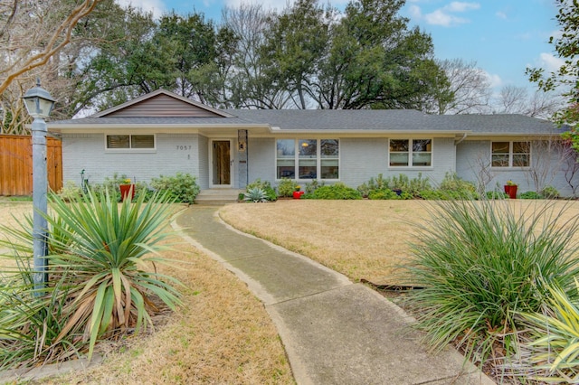 single story home with a front yard, brick siding, and fence