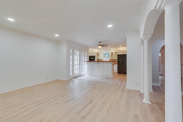 unfurnished living room with baseboards, arched walkways, ornamental molding, light wood-type flooring, and ornate columns