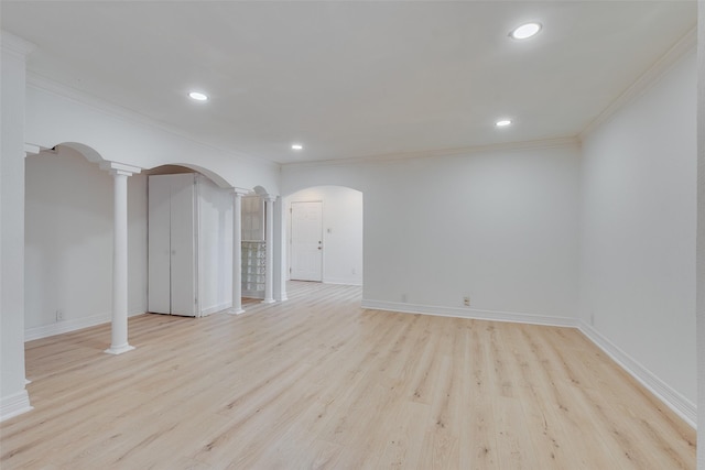 empty room featuring arched walkways, ornamental molding, decorative columns, and light wood-style floors